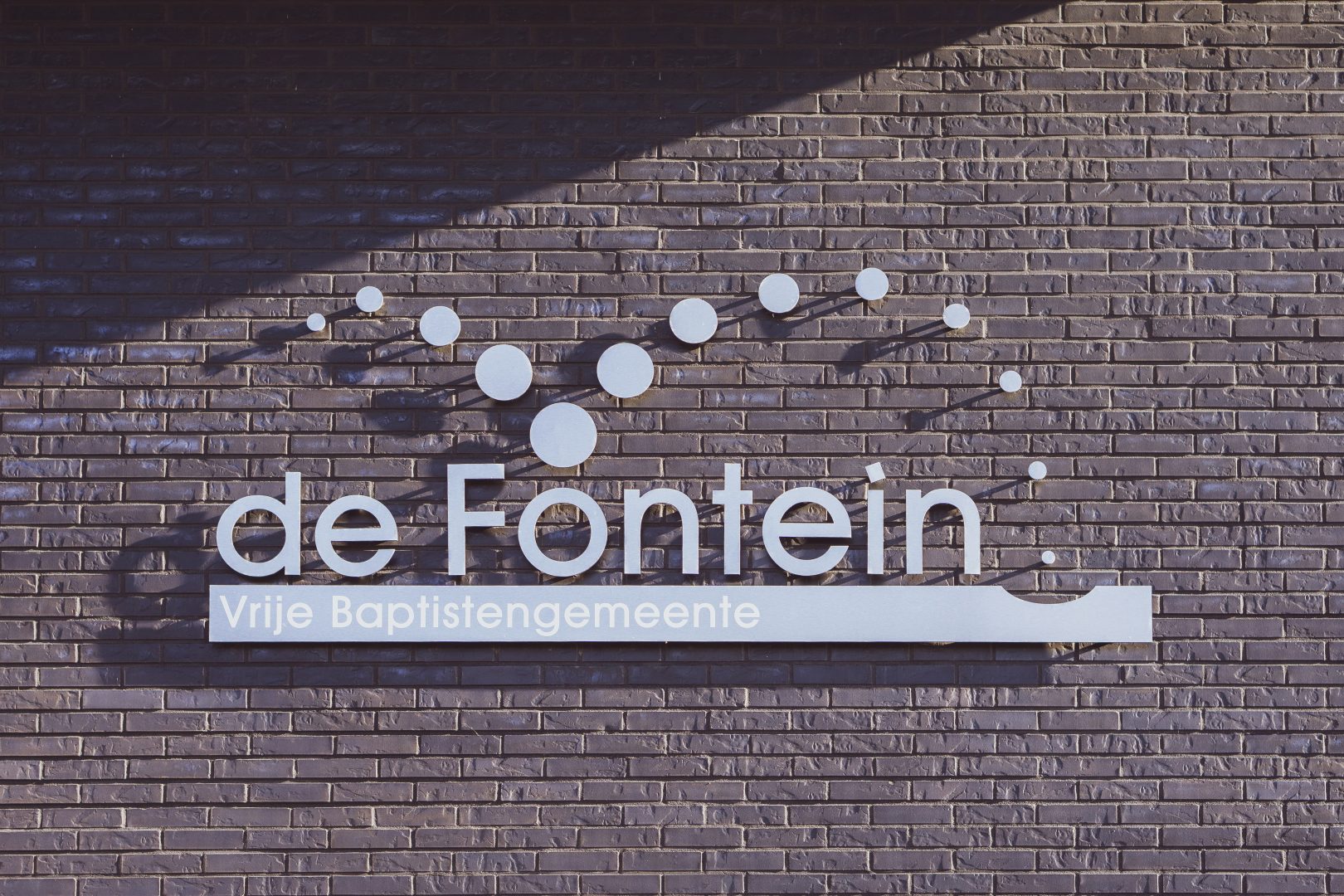 Logo “Vrije Baptistengemeente de Fontein” op muur